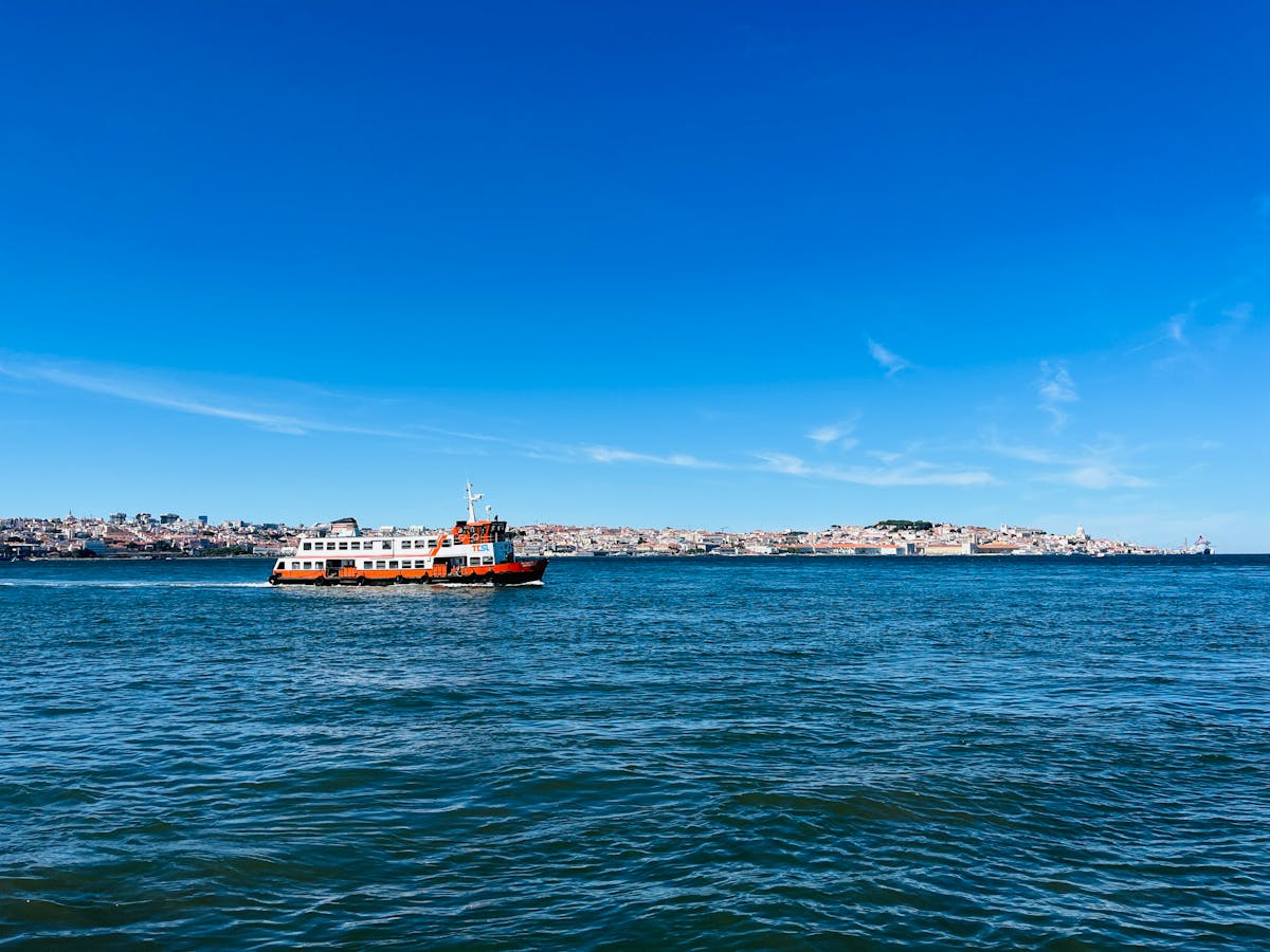 A ferry crossing the Tagus River with Lisbon skyline in the background