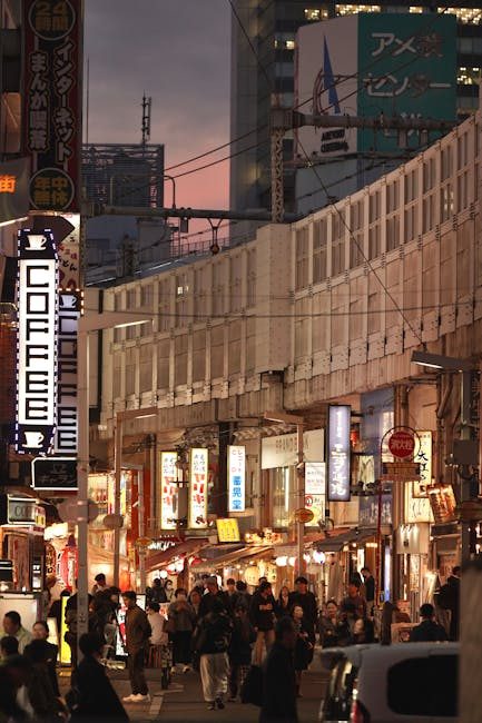 Bustling evening street scene in Tokyo with neon signs, shops, and lively crowds.