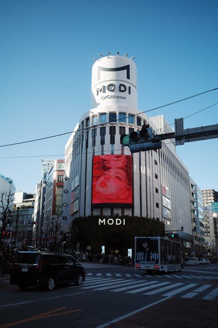 MODI building in Shibuya, Tokyo, with digital billboards under a clear blue sky.