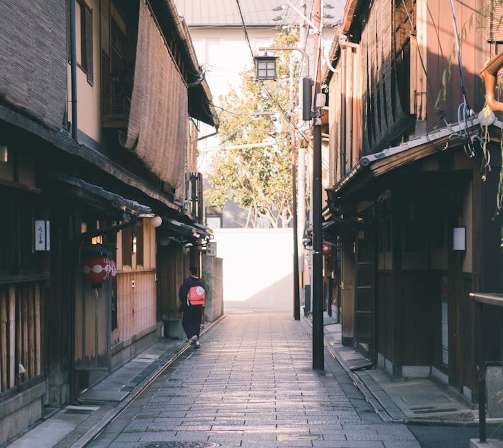 A picturesque narrow alley in Gion, Kyoto, showcasing traditional Japanese architecture on a sunny day.