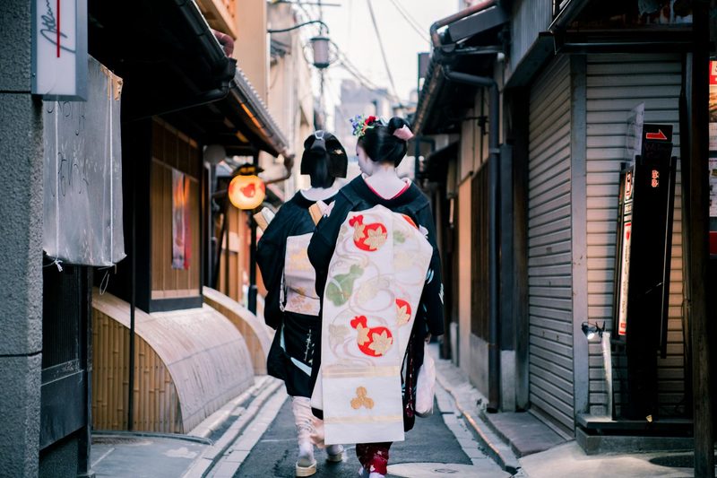 Japanese women in kimonos walking through a Kyoto alley