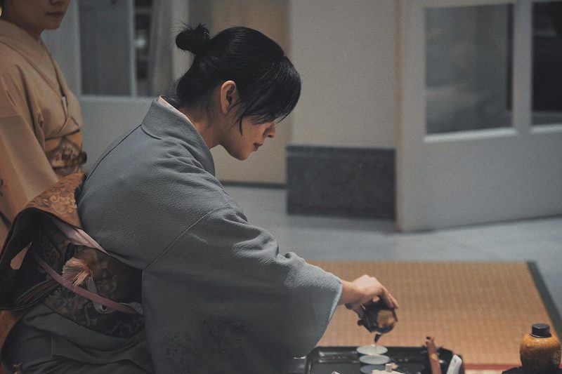 Woman in kimono performing traditional Japanese tea ceremony