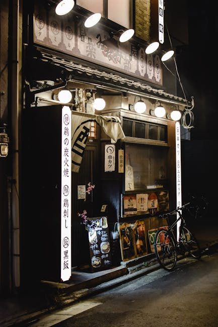 Cozy traditional Japanese street eatery with bicycle in Kyoto, Japan, illuminated at night.