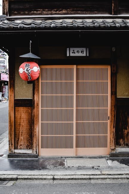 Capture of a classic Japanese entrance with a red lantern in Kyoto, showcasing traditional architecture.