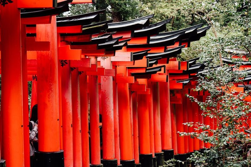 Explore the vibrant red torii gates at Fushimi Inari Shrine in Kyoto, Japan, surrounded by lush greenery.