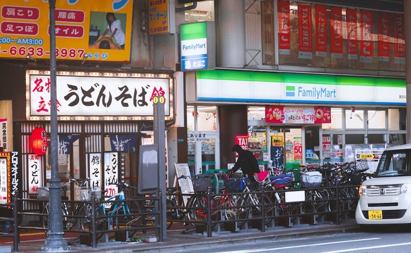Japanese street scene with a FamilyMart and Udon shop, bicycles parked in front.