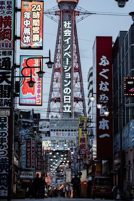 Vibrant street scene in Osaka featuring the iconic Tsūtenkaku Tower with colorful signage and lively atmosphere.