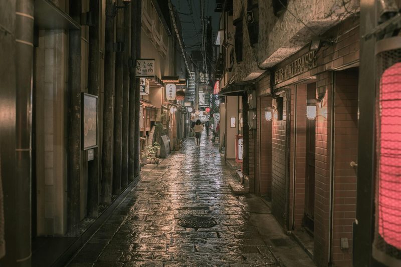 Moody narrow alley at night in Osaka with wet cobblestone
