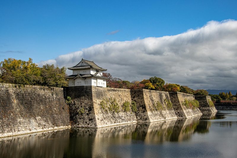 Osaka Castle stone walls reflecting on the calm moat water