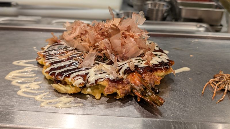 Okonomiyaki, a Japanese savory pancake, cooking in Osaka