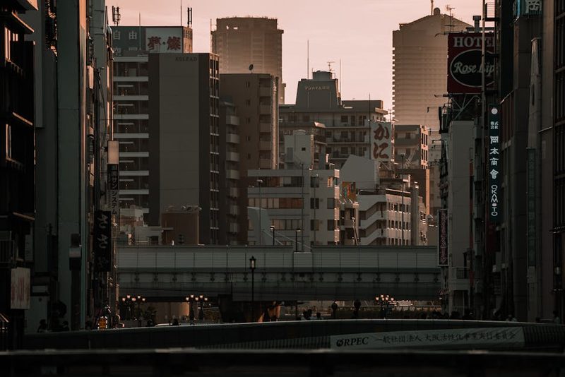 Cityscape of Osaka's business district with towering buildings at sunset, capturing vibrant city life.