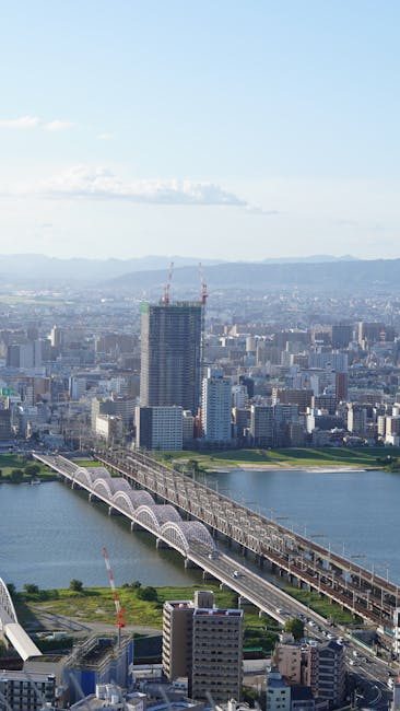 Stunning aerial view of Osaka cityscape featuring bridges over a river under a clear blue sky.
