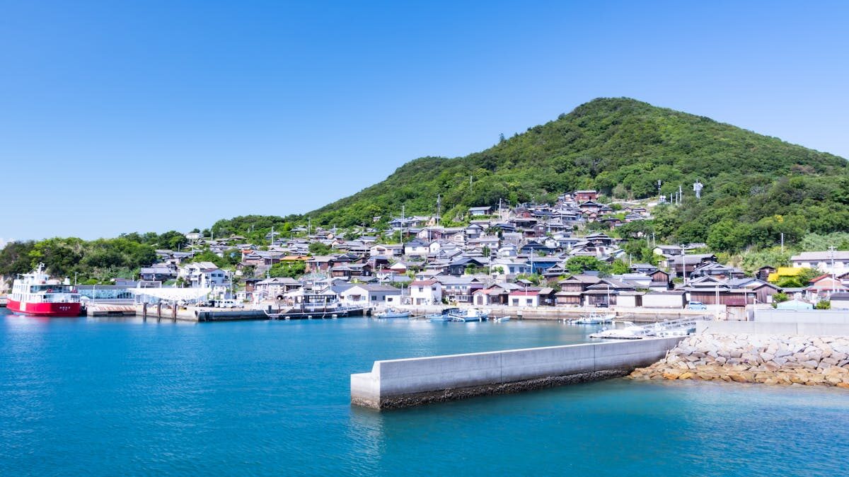 Small Japanese coastal village with fishing boats moored along the waterfront, typical of the Seto Inland Sea islands