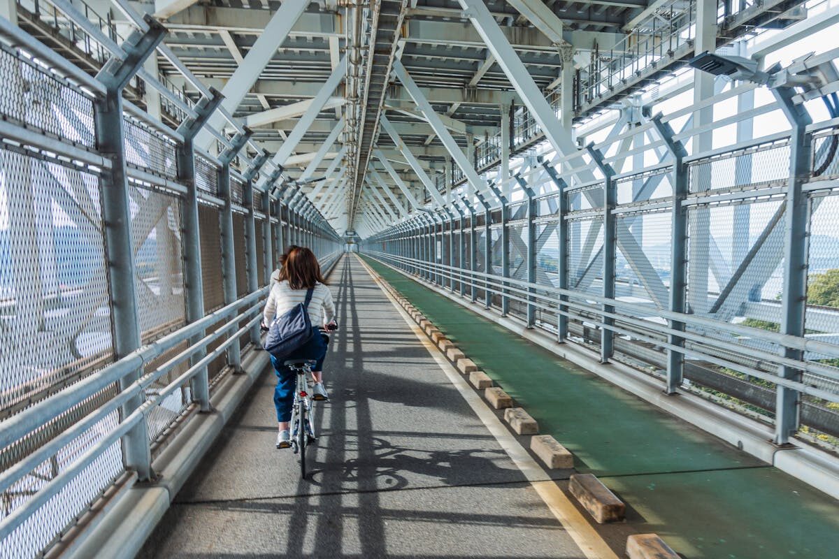 Woman cycling along the dedicated bike lane on Innoshima Bridge with the sea visible below