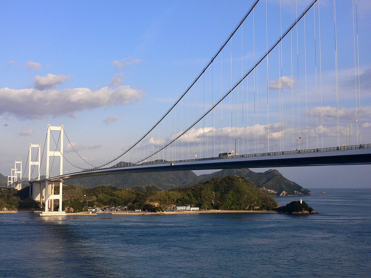Kurushima-Kaikyo Bridge spanning the narrow Kurushima Strait with clear water below and Imabari visible in the distance
