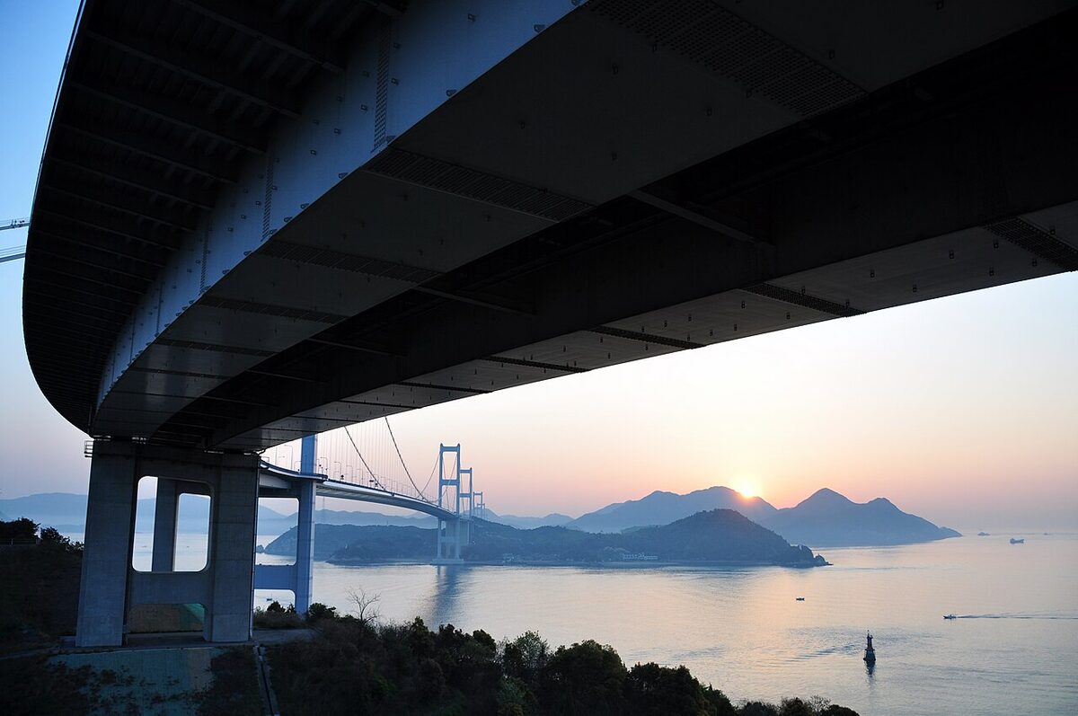 Kurushima-Kaikyo Bridge silhouetted against an orange sunset sky over the Seto Inland Sea