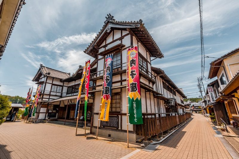 Charming street with historic Japanese architecture and vibrant banners under a clear sky.