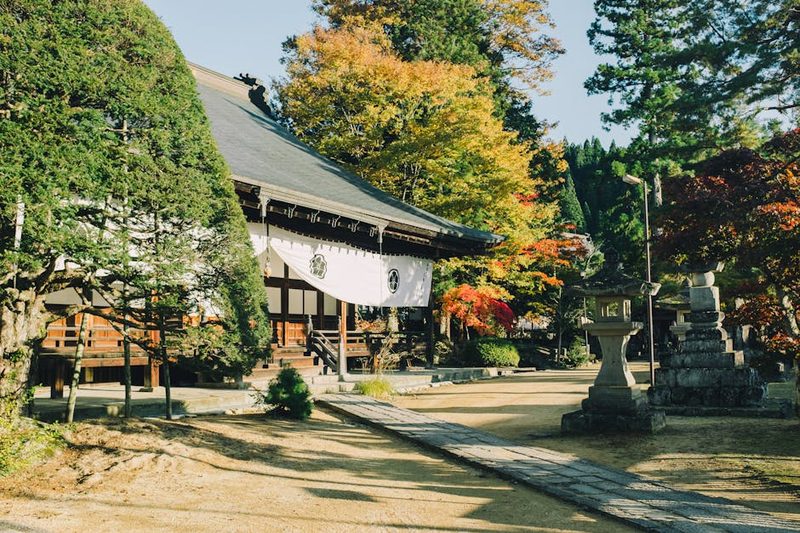 Peaceful Buddhist temple set against vibrant fall colors in Takayama, Japan.