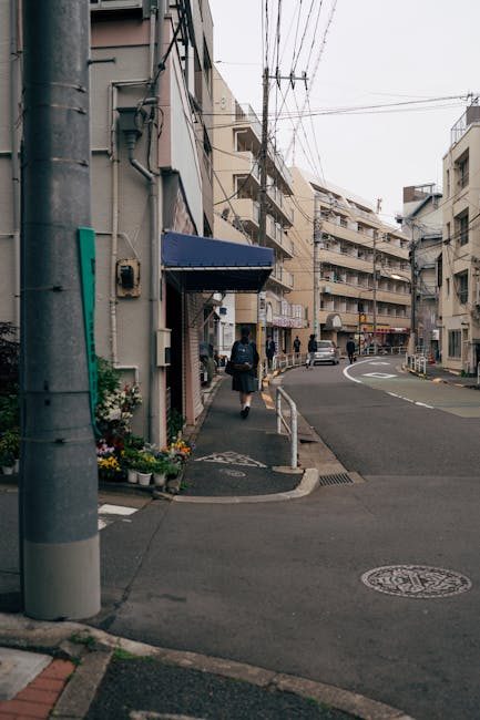 Street scene in Tokyo with a pedestrian walking past urban buildings, showcasing daily city life.