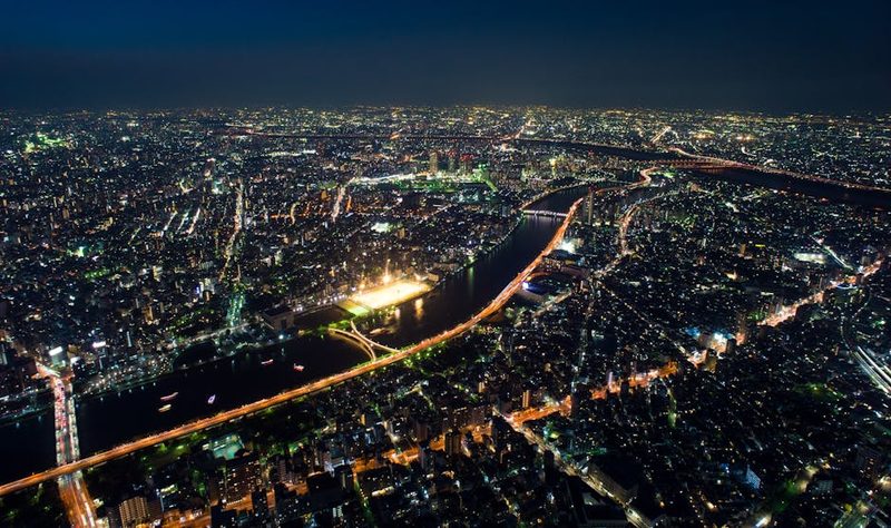 Stunning aerial view of Shinjuku, Tokyo with city lights and river at night.