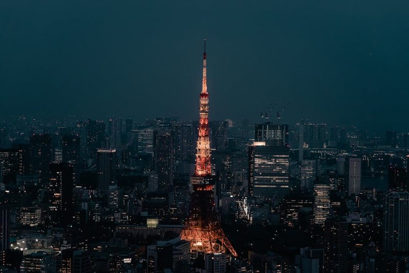 Stunning view of Tokyo Tower lit up at night, surrounded by the urban skyline of Minato City, Tokyo.