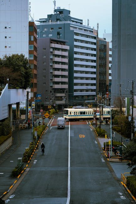 Street scene capturing a tram and cyclist in Tokyo amid tall buildings.
