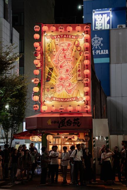 Explore the bustling nightlife at Yataien Izakaya in Shinjuku, Tokyo. Bright neon lights attract a lively crowd.