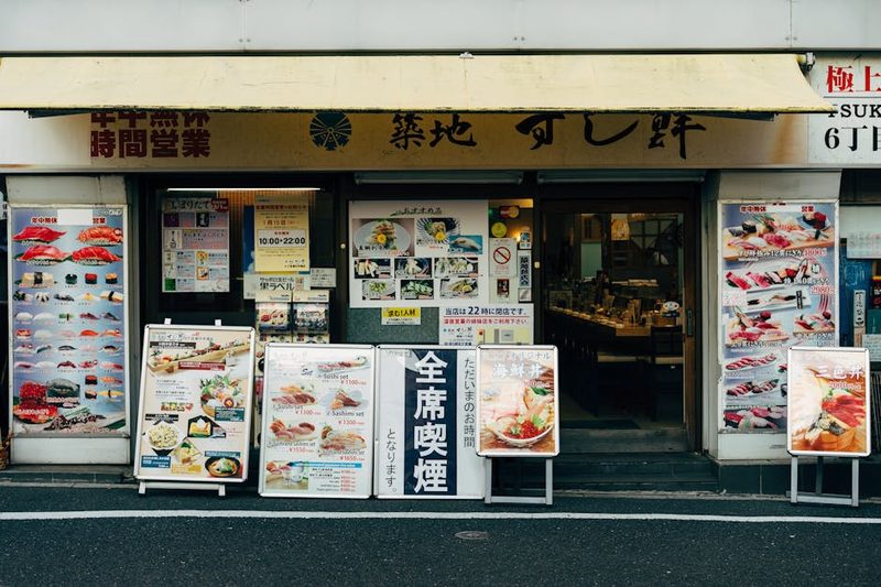 Front view of a traditional sushi restaurant in Tokyo with vibrant menu displays.
