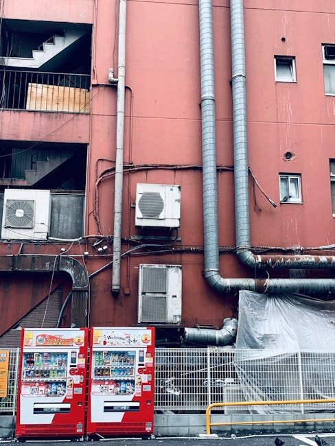 Red vending machines against an urban wall in Minato City, Tokyo, showcasing modern city life.