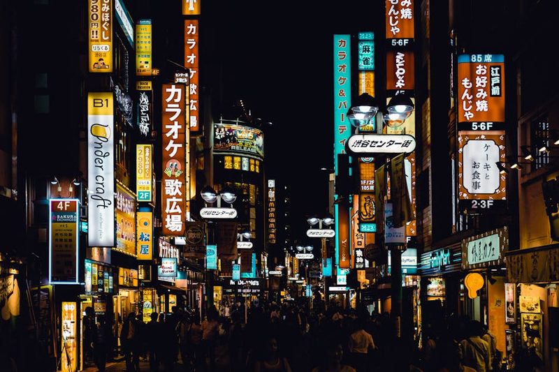 Bustling Shibuya street at night with bright neon signs and crowds, showcasing Tokyo's vibrant nightlife.