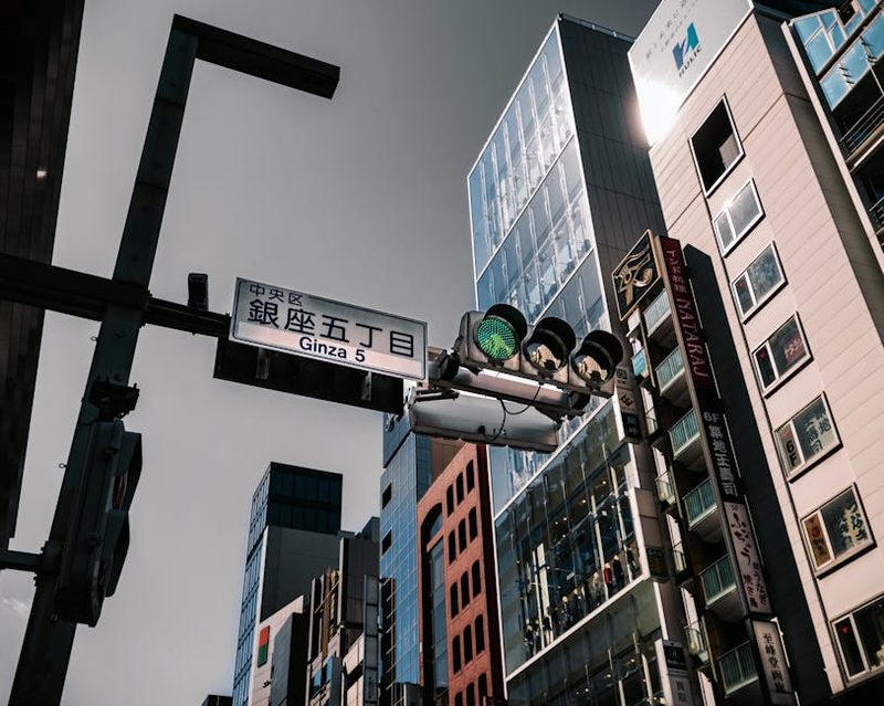 Urban scene at Ginza 5 in Tokyo showing skyscrapers and traffic lights under a clear sky.