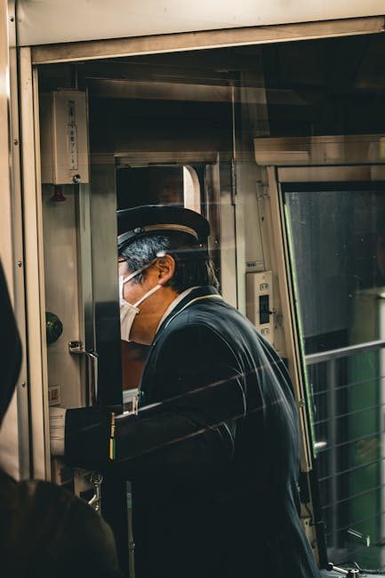 A train conductor wearing a mask performs duties inside a train in Kamakura, Japan.
