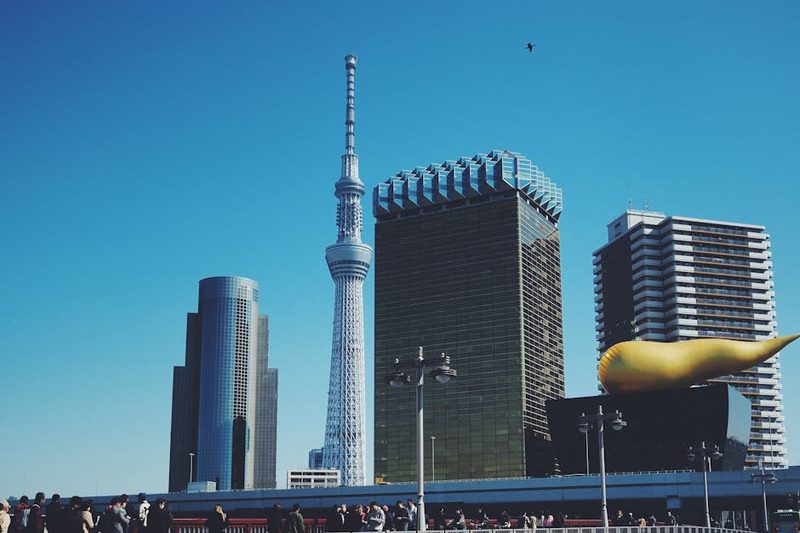 Skyline featuring Tokyo Skytree and Asahi Beer Hall under clear blue sky in Tokyo, Japan.