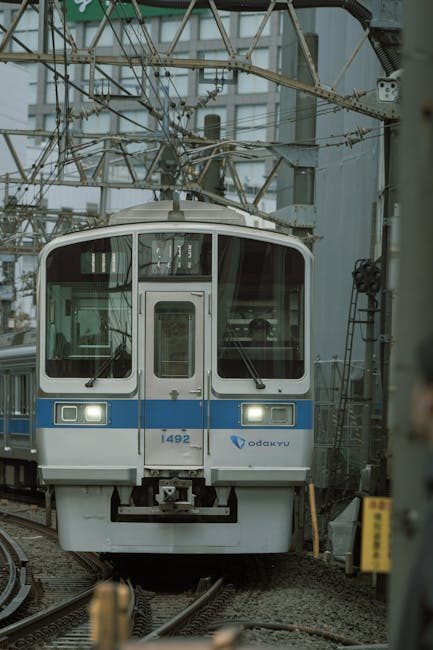 Odakyu train on tracks in Tokyo, showcasing urban transit with visible cables and buildings.