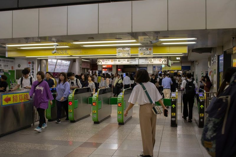A crowded entrance of a Tokyo subway station with commuters passing through ticket gates.