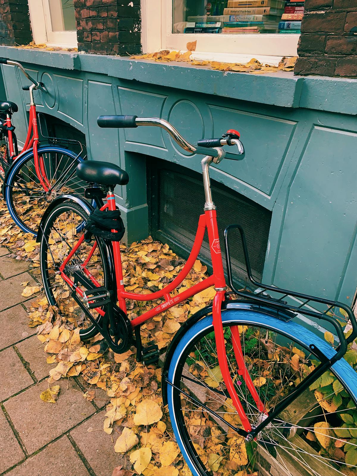 A red bicycle parked against a blue Amsterdam building