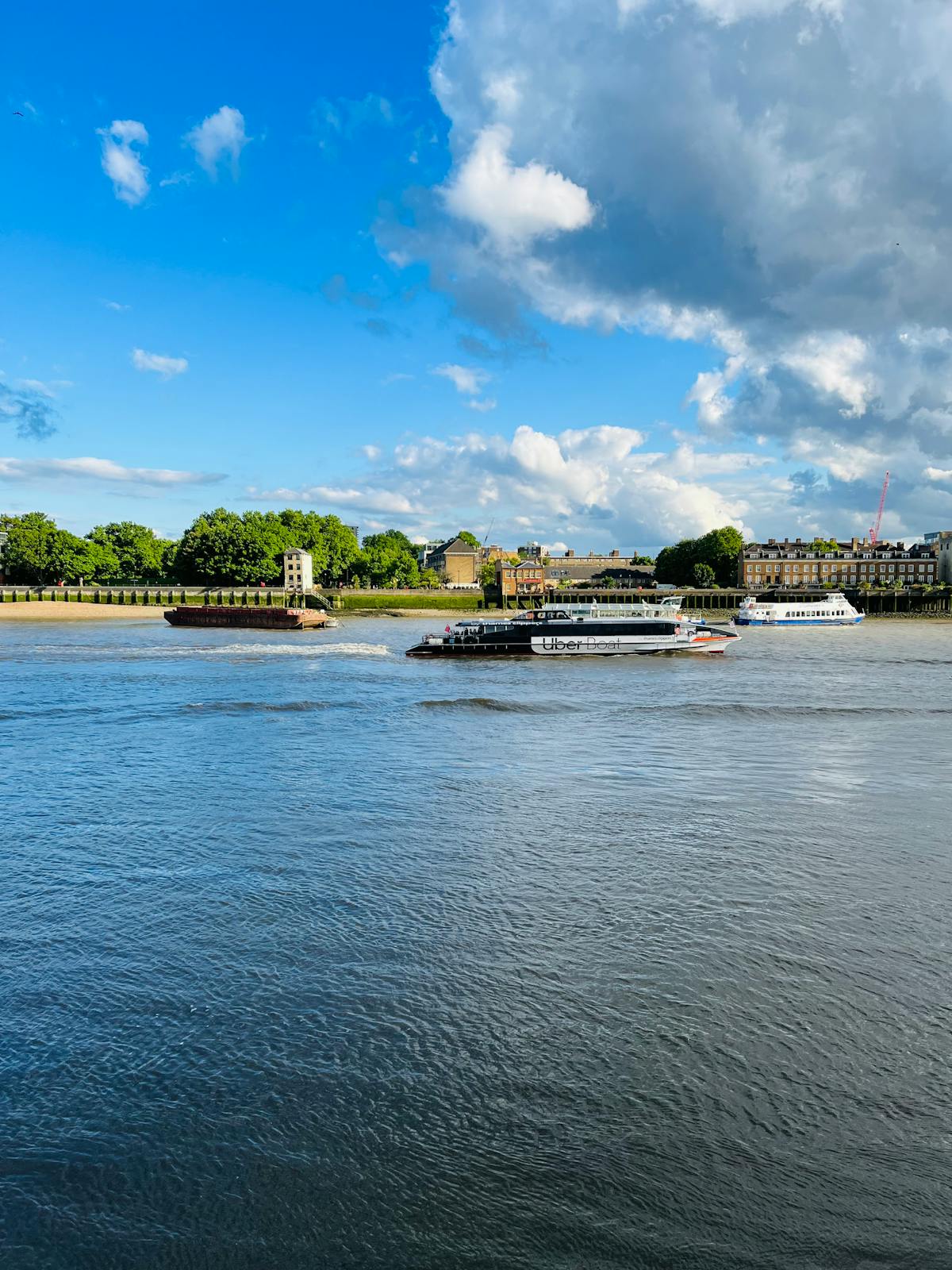 Various boats on the River Thames under a bright sky