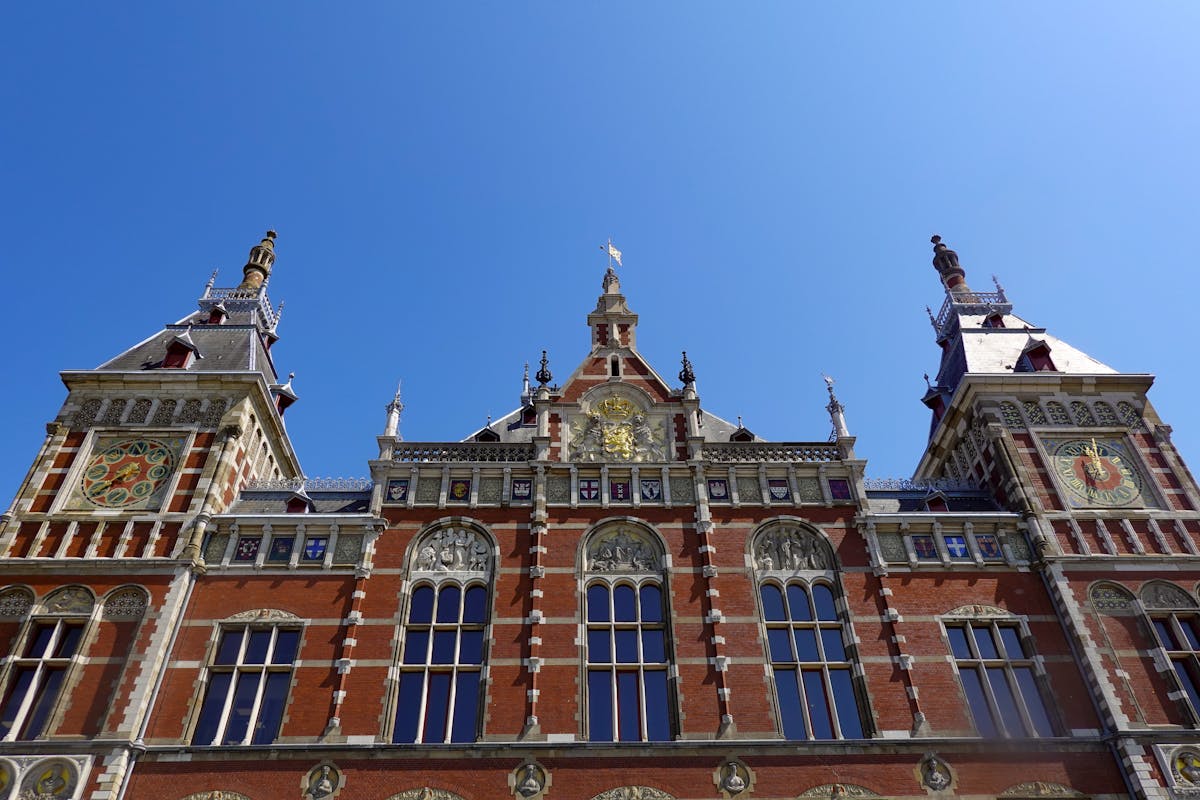 Ornate facade of Amsterdam Centraal Station under blue sky