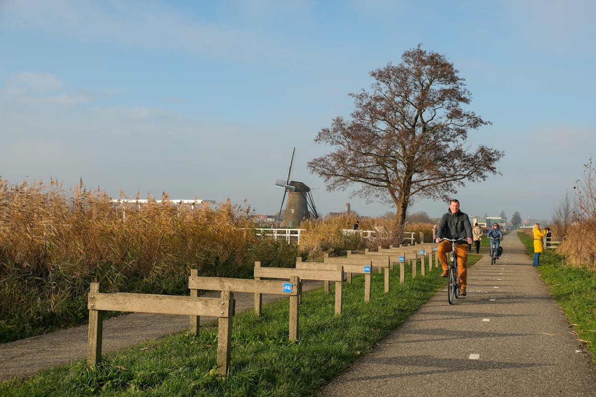 Cyclists riding past a Dutch windmill on a sunny day