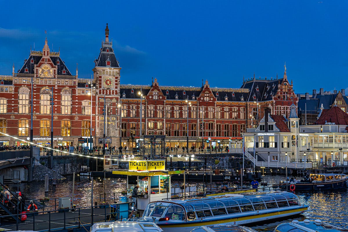 Amsterdam Central Station illuminated against evening blue sky