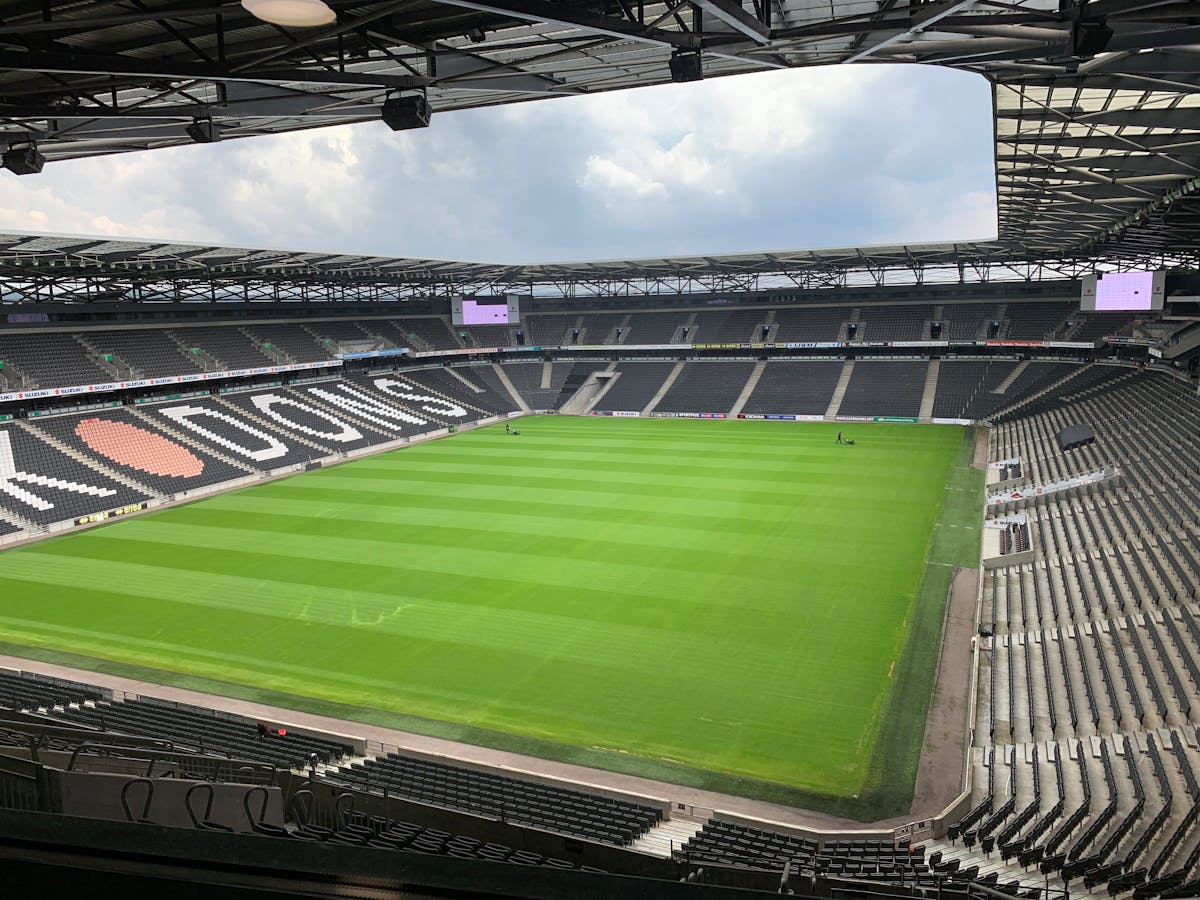 Empty football stadium with a bright green pitch and rows of seats