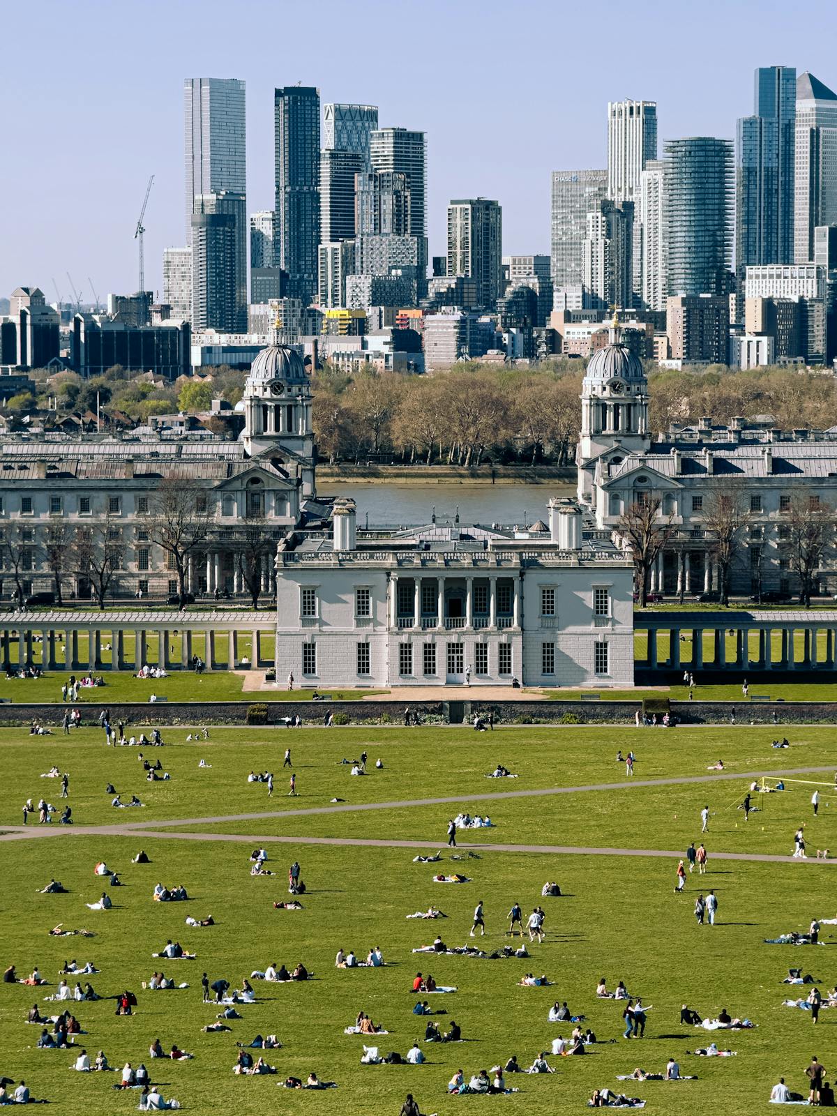 People enjoying Greenwich Park with London skyline in background