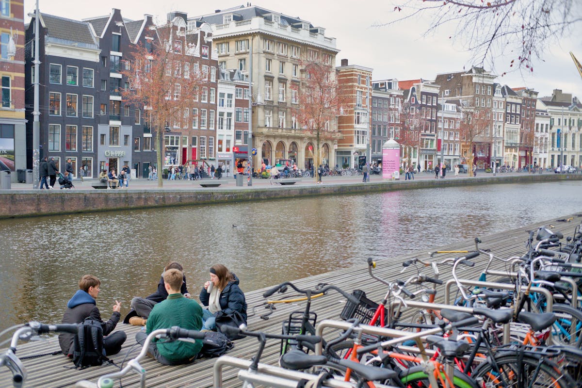Friends relaxing by an Amsterdam canal with bikes nearby