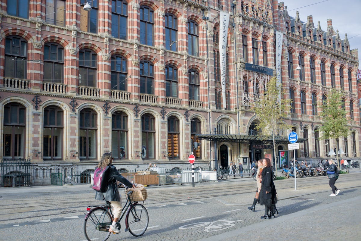 Cyclists and pedestrians near Magna Plaza historic building in Amsterdam