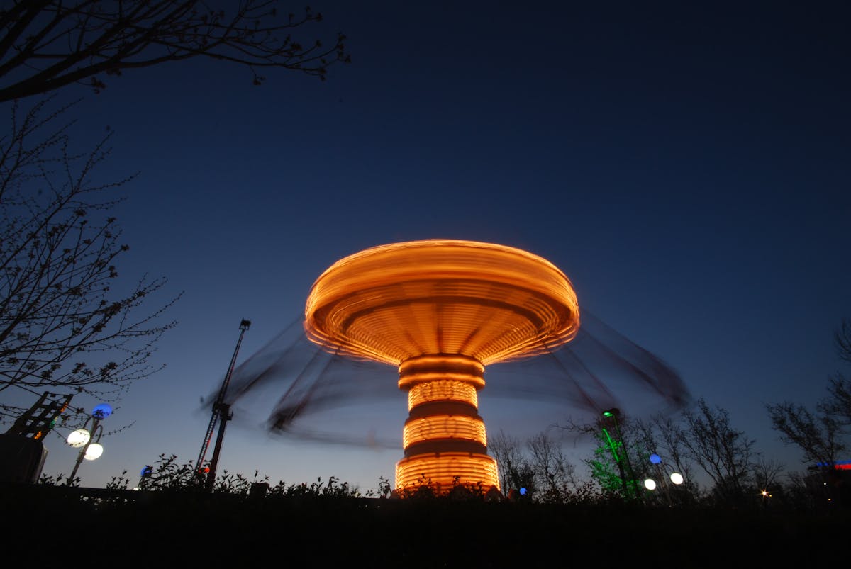 Long exposure photo of an illuminated swing ride at night capturing motion blur