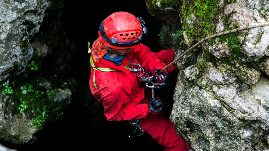 Caver in red gear climbing on rocks Budapest tour