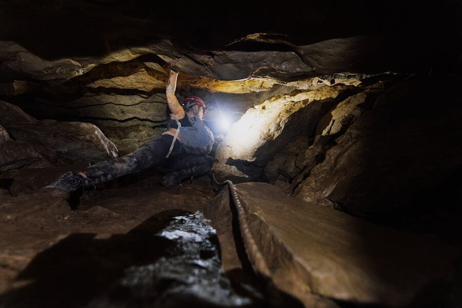Caver navigating with headlamp through limestone passage Budapest