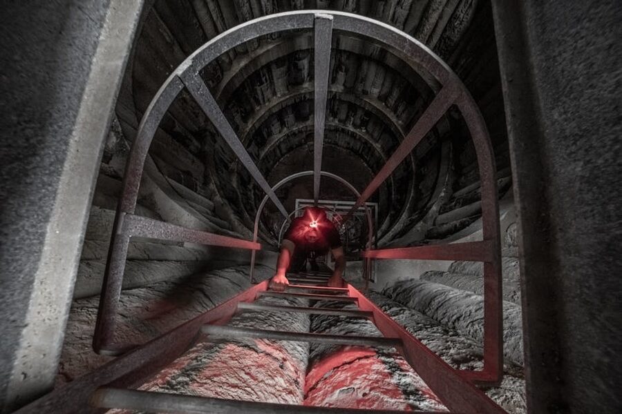 Caver climbing ladder in dark tunnel