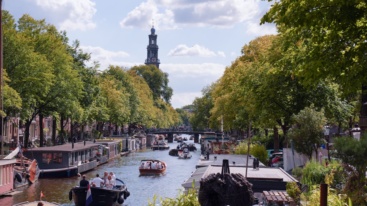 Amsterdam canal scene with the Westerkerk church tower, canal boats, and historic buildings
