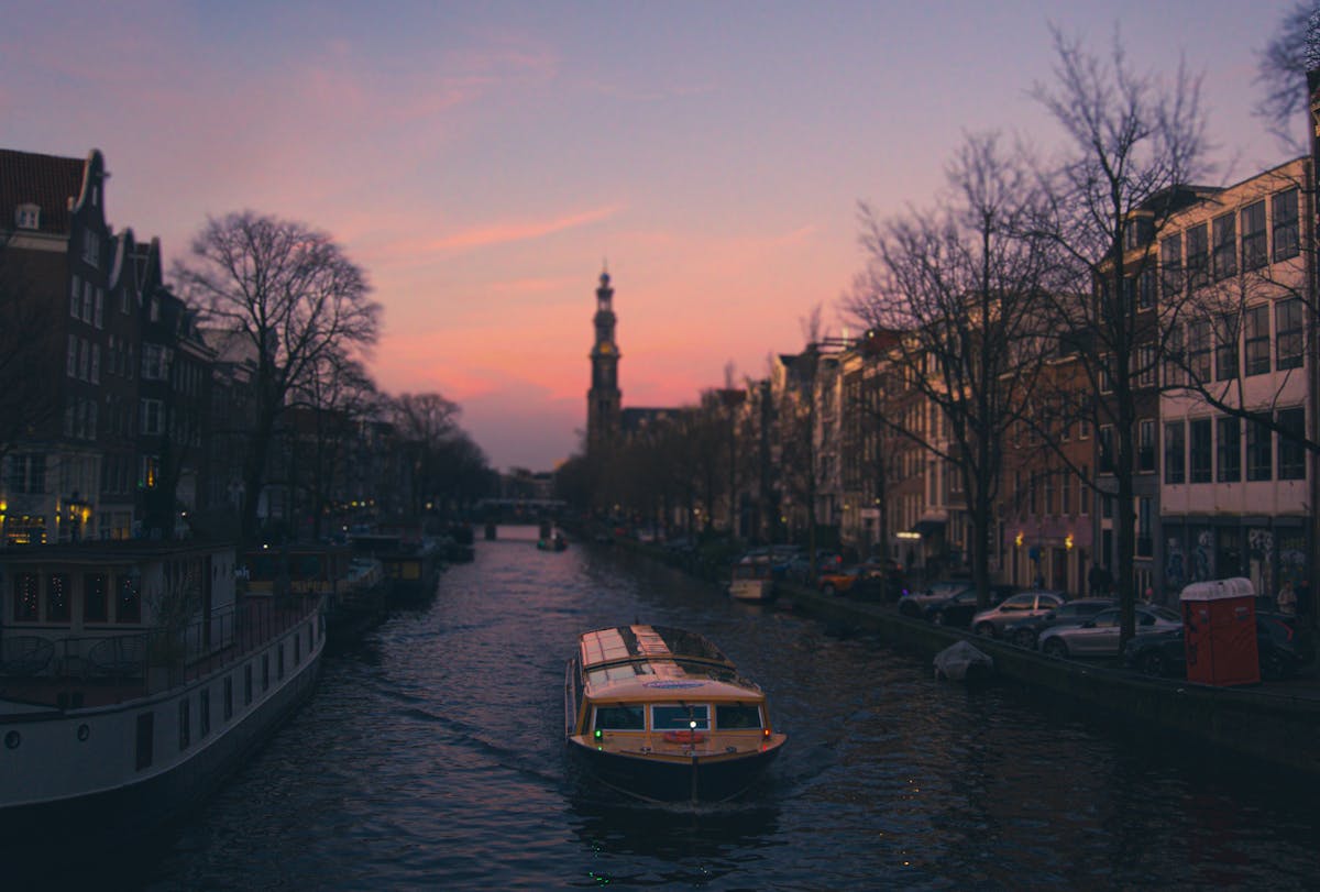 Amsterdam canal at golden hour with a tour boat and historic buildings